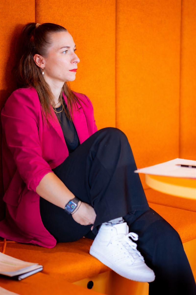 Katrin Verena Hentschel im pinken Blazer vor einer orangen Wand